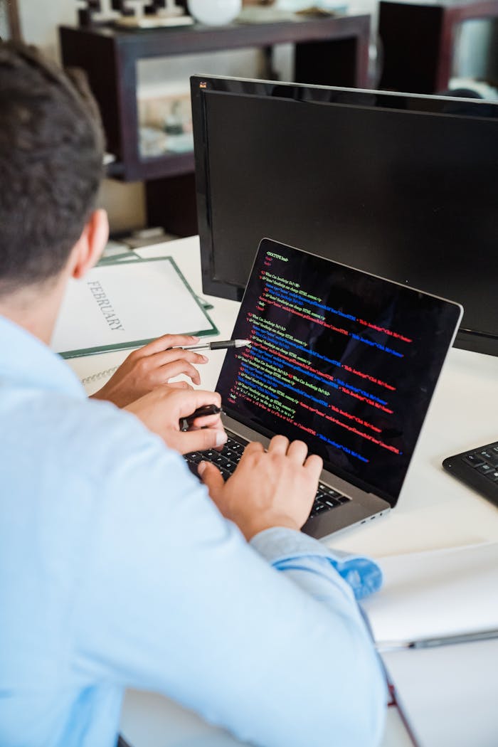 An office worker intensely typing code on a laptop, showcasing programming skills.